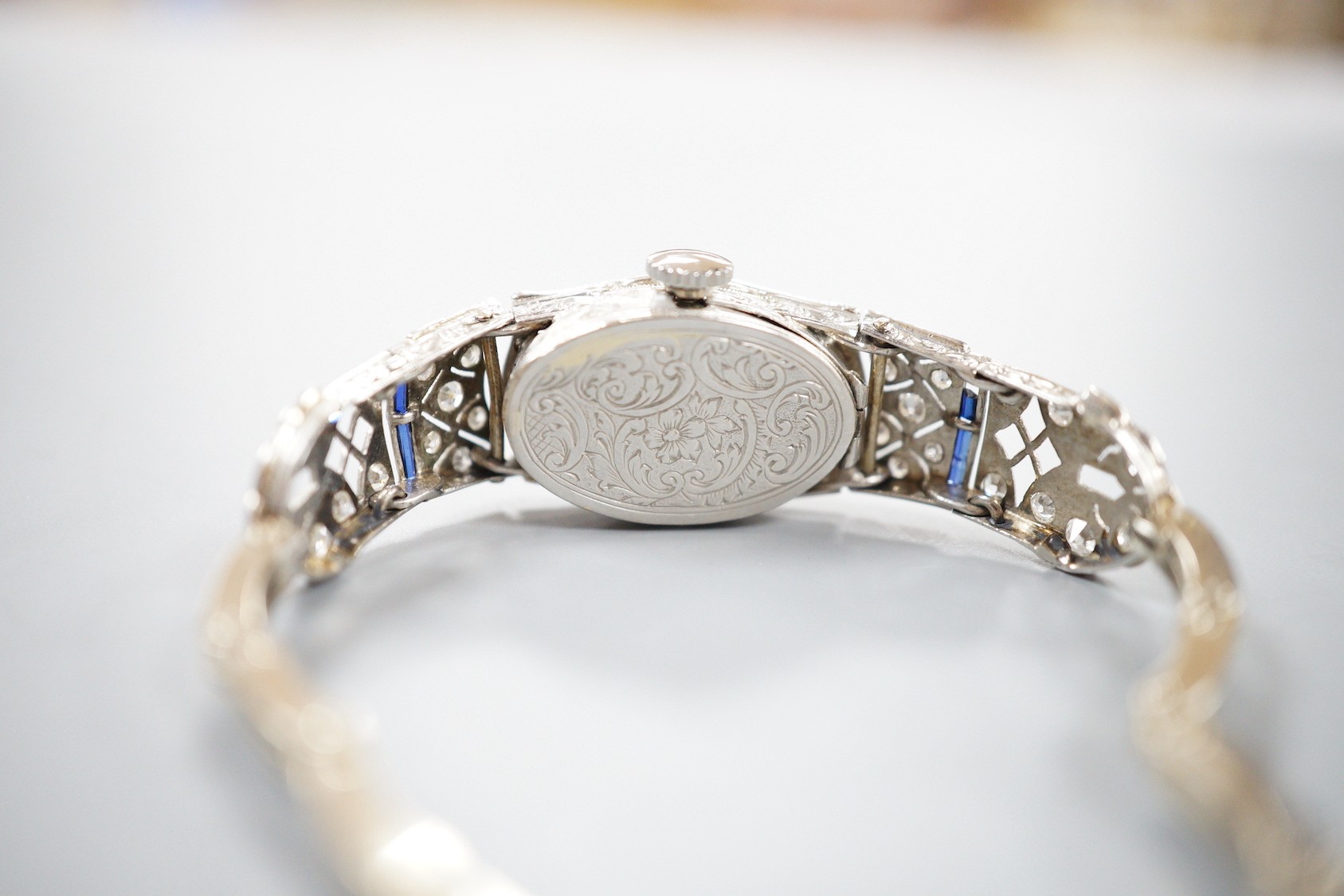 A lady's mid 20th century white metal, sapphire and diamond cluster set cocktail watch, on a 9ct bracelet (a.f.), gross weight 17.2 grams.
